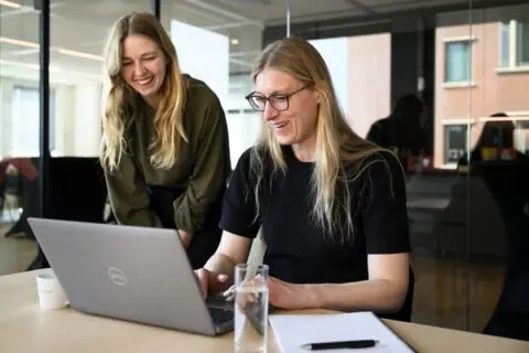 twee vrouwelijke collega's in overleg achter een laptop