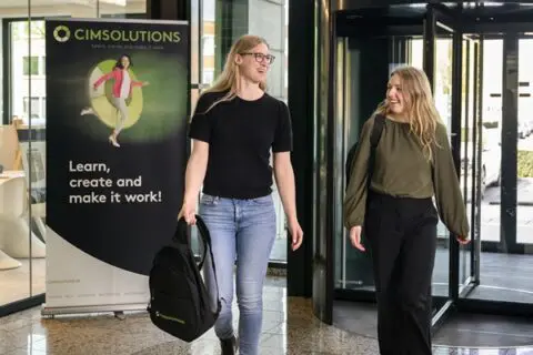2 vrouwelijke CIMSOLUTIONS collega's lopen het kantoor binnen