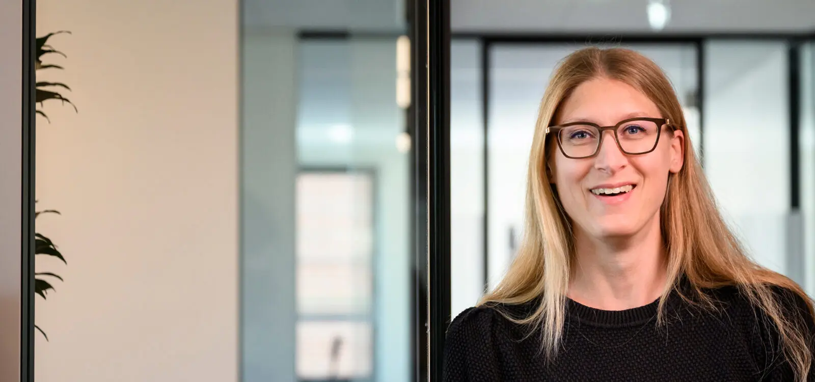 Vrouwelijke CIMSOLUTIONS collega kijkt lachend in de camera